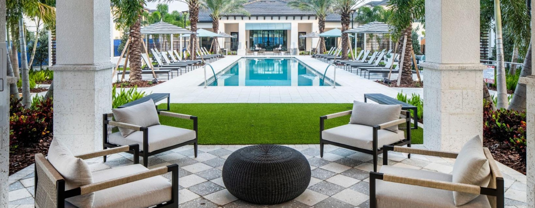 a swimming pool with chairs and a deck with trees and a building in the background at Jefferson Lake Howel Apartments in Casselberry, FL